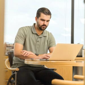 Zdjęcie ilustrujące mężczyznę pracującego na laptopie